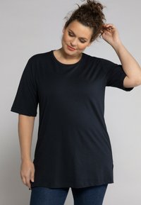 Tunic nera a maniche corte con scollatura rotonda, realizzata in un tessuto liscio, con spacchi laterali per facilitare il movimento.