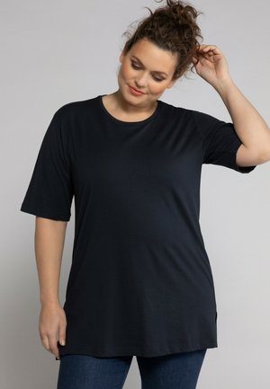 Tunic nera a maniche corte con scollatura rotonda, realizzata in un tessuto liscio, con spacchi laterali per facilitare il movimento.