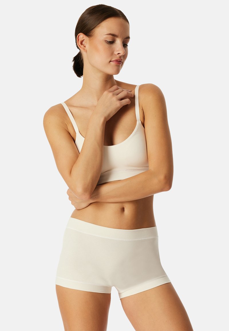 Cremfarbener nahtloser Bralette- und Boyshorts-Satz, hergestellt aus weichem, dehnbarem Material mit dünnen Trägern und einem breiten elastischen Bund.