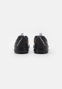 Schwarze Fußballschuhe mit weißen und goldenen Akzenten, ausgestattet mit einem strukturierten Obermaterial, einem auffälligen Markenzeichen und einer strapazierfähigen Gummisohle.