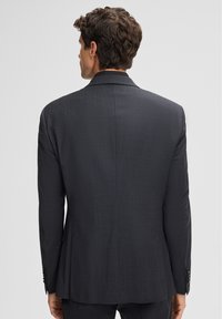 Donkergrijze colbert, gestructureerde stof, enkel-breasted ontwerp, geknipte revers, twee knopen en een split aan de achterkant.