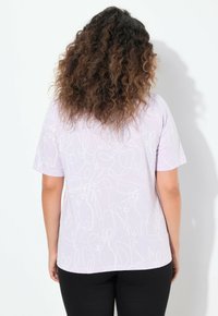 Camiseta de color púrpura claro con un dibujo continuo de conejos en línea blanca, de mangas cortas, con cuello redondo y un ajuste relajado.