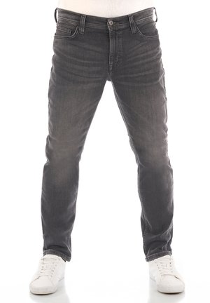 Jeans de denim gris con fit ajustado, cinco bolsillos y un leve desgastado, combinados con zapatillas blancas. Incluye cierre de botón y cremallera.