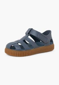 Dark blue rubber sandal with a closed toe, multiple cutouts, adjustable strap, and textured brown outsole. Features logo on strap.