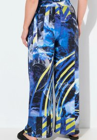 Wijduitlopende broeken met een levendig blauw en zwart abstract patroon met gele en blauwe strepen. Gemaakt van lichtgewicht stof met een gladde textuur.