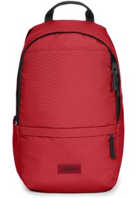 Sac à dos en tissu rouge avec une texture lisse, doté d'une poignée supérieure, de bretelles ajustables et d'une poche avant zippée. Logo Eastpak visible.