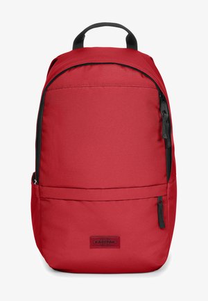 Sac à dos en tissu rouge avec une texture lisse, doté d'une poignée supérieure, de bretelles ajustables et d'une poche avant zippée. Logo Eastpak visible.
