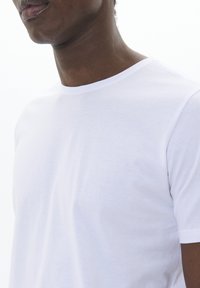 Balta crewneck marškinėliai, pagaminti iš lygios medvilnės. Trumpomis rankovėmis ir standartinio kirpimo, su minkšta, minimalistine tekstūra, tinkami kasdieniam dėvėjimui.