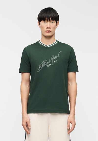Πράσινο βαμβακερό t-shirt με V-λαιμό και αντίθετη λευκή διακόσμηση. Διαθέτει κεντημένο λογότυπο μπροστά, κοντά μανίκια και κανονική εφαρμογή.