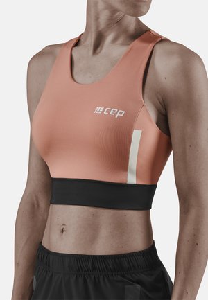 Roze sportbeha met een zwarte band, met een witte verticale streep en het "cep" logo. Gemaakt van rekbare, gladde stof, ontworpen voor comfort.
