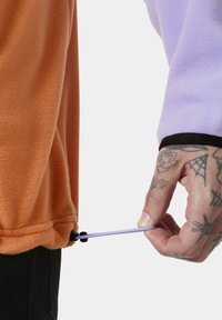 Fleece pullover met oranje en lavendel kleurblokken, voorzien van een verstelbare toggle aan de zoom en zichtbare stikseldetails.