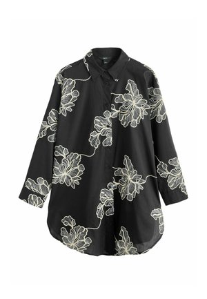 Chemise noire à manches longues avec boutons, ornée d'un grand motif floral brodé en écru et dotée d'un col pointu.