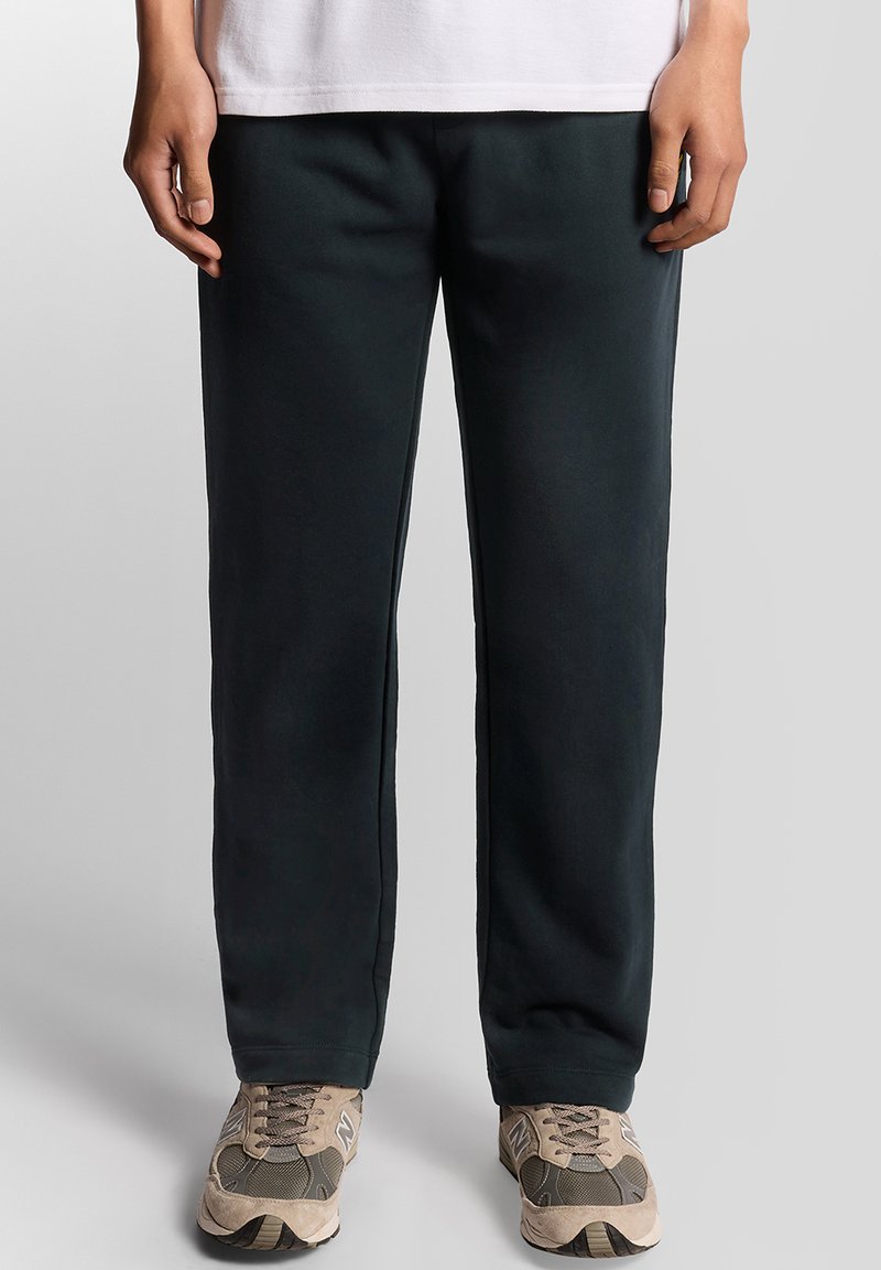 Mörkgröna sweatpants i mjuk tyg med avslappnad passform. Har sid sömmar och öppna fållar; matchas med beiga sneakers.