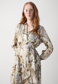 Rochie înfășurată cu mâneci, dintr-un material ușor, având un model floral în nuanțe de verde și albastru, cu un cordon de legare și un guler clasic.