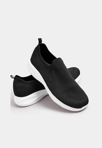 Schwarze Slip-On-Sneaker mit gestrickter Textur, ausgestattet mit einer weißen Sohle und einem Zugband an der Rückseite für ein einfaches Anziehen. Leichtes Design für Komfort.