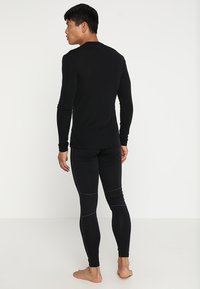 Czarny długi rękaw bluzka i legginsy, dopasowany krój, gładka tekstura, z kontrastującymi szwami i siateczkowymi detalami na legginsach.