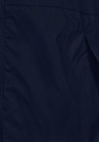 Tissu léger bleu marine avec une texture lisse ; présente une fermeture éclair et des coutures minimales, conçu pour le confort et la fonctionnalité.