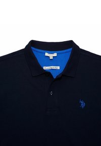 Polo oscuro azul marino con dos botones, logo bordado en azul de caballo y jinete en el pecho, y forro interior de cuello azul.