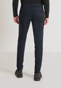 Pantaloni attillati blu navy realizzati in un tessuto liscio, dotati di due tasche posteriori e di un design a gamba dritta.