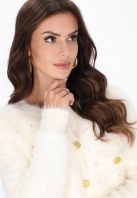 Cardigan bianco morbido con finitura testurizzata, caratterizzato da decorazioni in oro e argento, polsini morbidi e scollatura arrotondata.