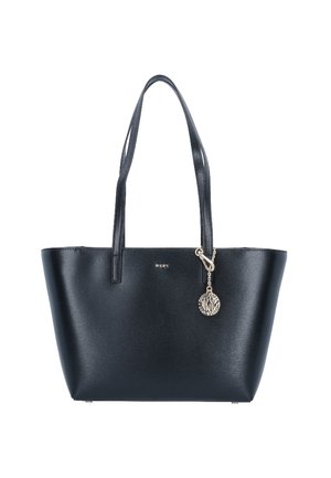 Sac cabas en cuir noir avec double bandoulière et un charme rond en argent attaché près du bord supérieur.