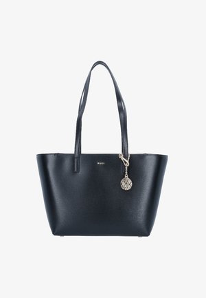 Sac cabas en cuir noir avec double bandoulière et un charme rond en argent attaché près du bord supérieur.