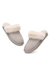 Beige suede slippers with a fluffy cream fur cuff, featuring a rounded toe and textured sole for grip. Soft, cozy lining visible.