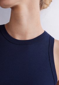 Marinblå ribbad linne med rund halslinning och ärmlös design, som har en slät yta och ren sömnad längs kanterna.