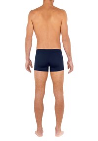 Boxers bleu marine en tissu doux, avec un design simple et une taille étroite. Vues de derrière, sur un modèle à la peau nue.