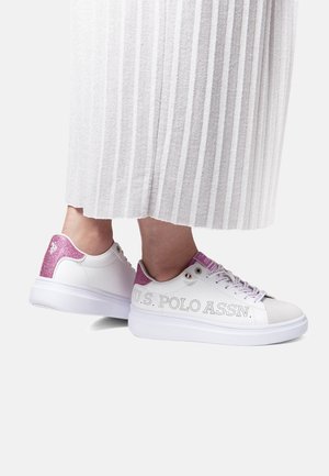 Zapatillas blancas con una textura suave, acentos de purpurina rosa en el talón y un detalle de marca perforado en el lateral. Suela plana blanca.
