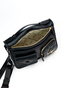 Borsa a mano in pelle nera con accessori in oro, dettagli trapuntati, molteplici scomparti con zip e una tasca frontale piatta. L'interno presenta una stampa del logo.