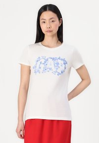 Weißes Baumwoll-T-Shirt mit rundem Ausschnitt. Verfügt über einen blauen Blumendruck, der das Wort "GAP" bildet. Kurze Ärmel, glatte Textur.