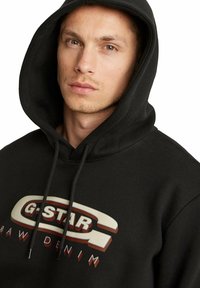 Felpa nera con cappuccio e logo G-Star grande e a contrasto in beige e rosso, dotata di cappuccio regolabile e texture in tessuto morbido.