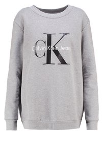 Grå crewneck sweatshirt i mjukt material, med en framträdande svart "CK"-logotyp och texten "Calvin Klein Jeans" i vitt.