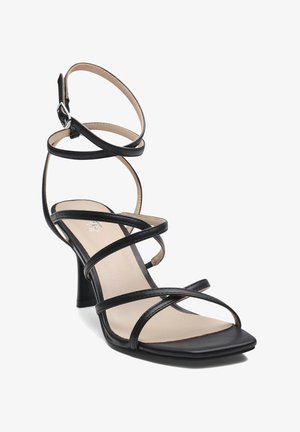 Sorte stropper høje hæle sandaler med firkantet tå og fleksible remme. Glat læderlignende materiale med en kontrasterende beige sål.