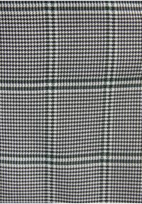 Zwart-wit houndstooth textiel met groene geruite accenten, met een gestructureerd patroon van kleine vierkanten en lijnen over het oppervlak.