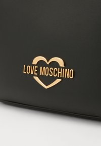 Czarna skórzana torba z złotym logo "Love Moschino" w motywie serca. Gładka tekstura i minimalistyczny design.