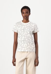 Hvit t-skjorte med korte ermer som har et svart blomstermønster, rund halslinning og en litt avslappet passform. Stoffet ser mykt ut med en jevn tekstur.