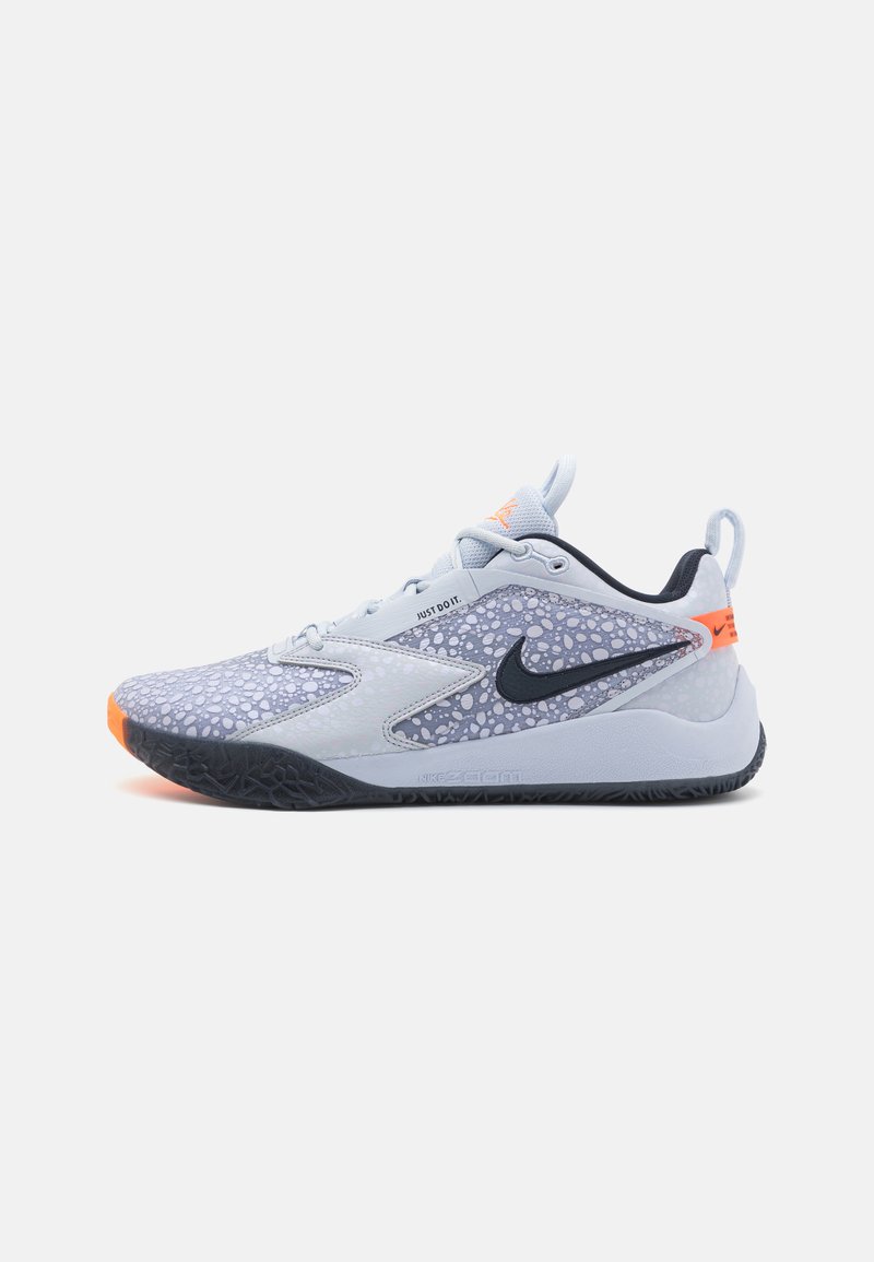 Scarpa sportiva Nike con tomaia grigia chiaro e dettagli a motivo, suola grigia scura e dettagli arancioni, progettata per prestazioni e comfort.