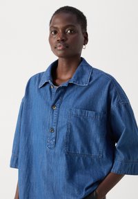 Dunkelblaue Jeanshemd mit Knopfleiste, Kragen und einer Brusttasche auf der linken Seite. Hat kurze Ärmel und einen lockeren Schnitt.