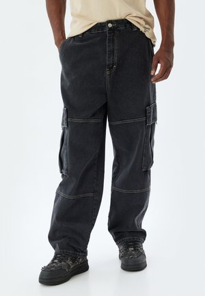 Sorte cargo-bukser med løs pasform, flere sidelommer og kontrasterende syninger. Fremstillet af slidstærk denim med en let tekstur.