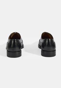 Zwarte leren schoenen met een gladde textuur, ronde neus en decoratieve stiksels. Lage hak en blootgestelde voeringdetails.