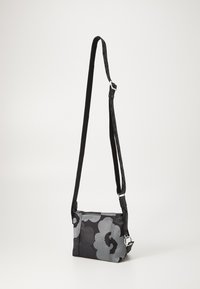 Black and gray floral crossbody bag with adjustable strap, boxy shape, textured fabric, and silver hardware accents.