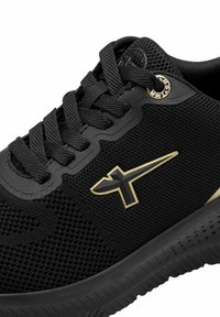 Black athletic shoe featuring a textured mesh upper, black laces, and a gold logo accent on the side. Rubber sole with a patterned tread.