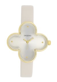 Montre en forme de fleur en or et argent avec un bracelet en silicone blanc. Présente des accents dorés et un cadran minimaliste avec trois aiguilles et des index horaires.