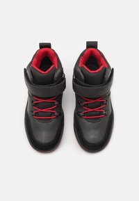 Černé a červené vysoké tenisky s hladkým koženým svrškem, textilní podšívkou, červenými tkaničkami a suchým zipem pro zapínání.