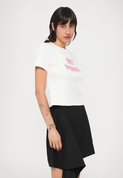 Valge lühendatud t-särk roosade tähtedega, kombineeritud musta asümmeetrilise seelikuga. Materjal on sile ja lõige mugav.