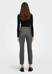 Pantaloni grigi su misura con una vestibilità slim, due tasche posteriori e una cintura piatta, abbinati a scarpe nere e a una maglia nera a maniche lunghe.