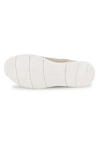 Shoe atlético em tom claro com um upper texturizado, apresentando uma sola de borracha branca, padrões de aderência em grade e um design ligeiramente curvado.