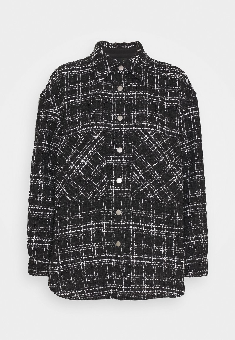 Veste à carreaux noir et blanc en tissu texturé, avec un col, des boutons à l'avant et deux poches avant, coupe ample.